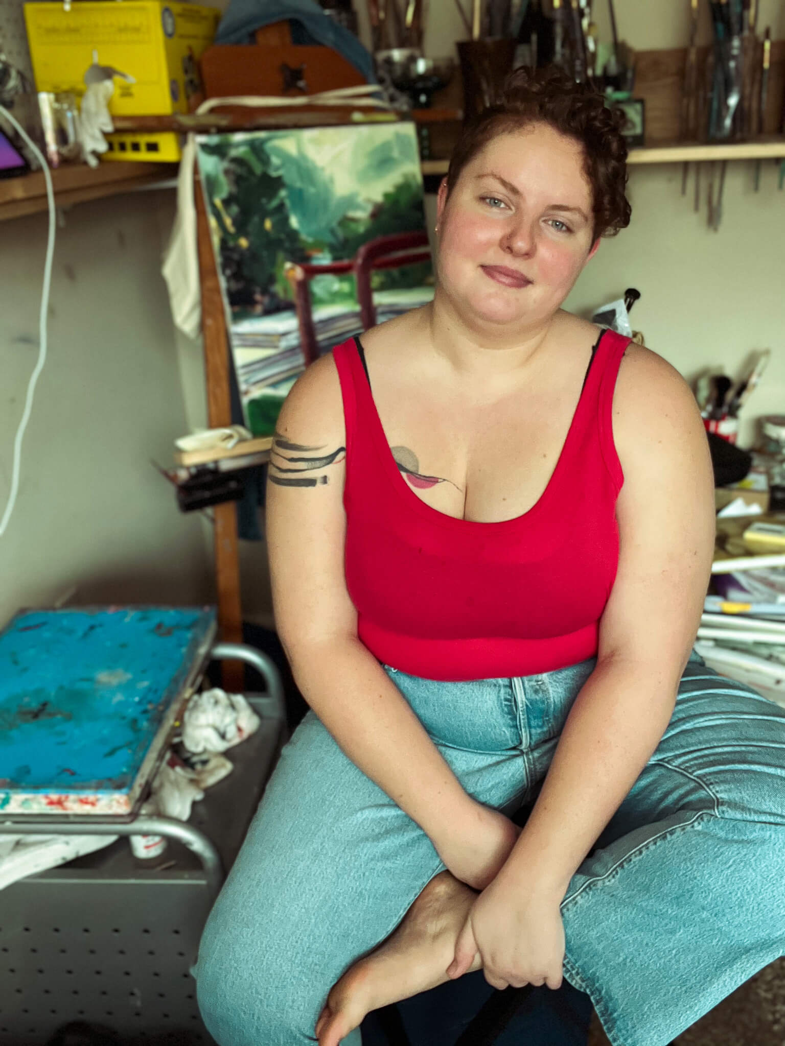 Tori Parrish sitting in front of easel and brushes